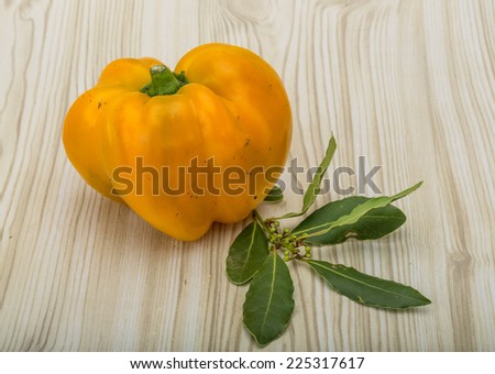 Yellow Bulgarian Pepper with laurel leaves on the wood background