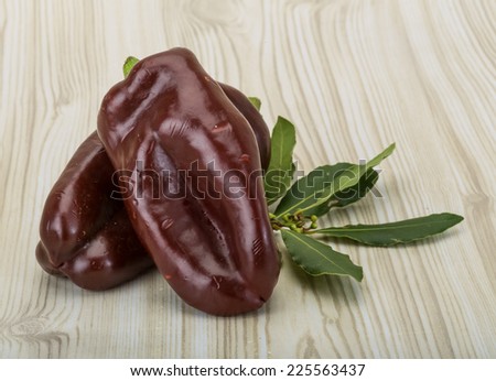 Brown Bulgarian pepper with laurel leaves on the wooden background