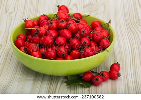 Hawthorn berries in the bowl on wood background