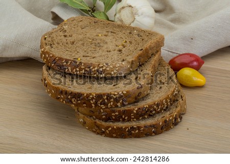 Cereal bread on the wooden background with cherry tomatoes