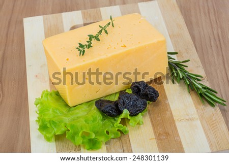Brick of yellow cheese with thyme and plum
