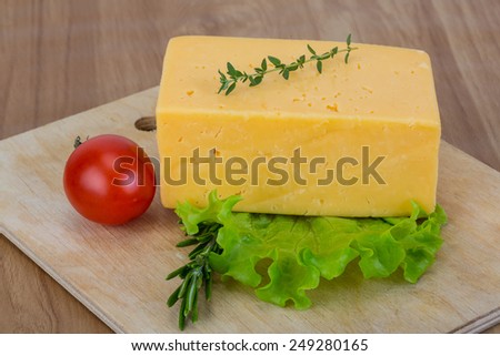 Brick of yellow cheese with thyme and plum