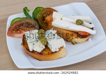 Tapas with soft blue cheese and black tomato