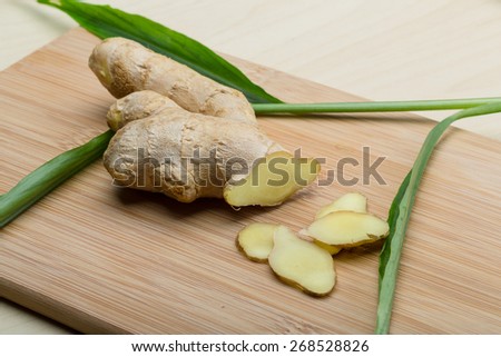 Ginger root on the wood background with leaves