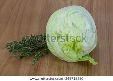Fresh Iceberg salad with thyme herbs on wood background