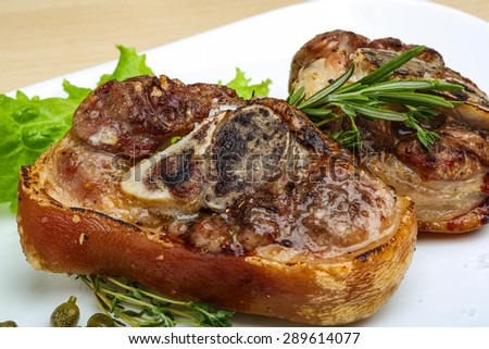 Roasted pork knee with thyme, rosemary and salad leaves