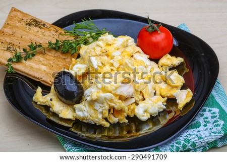 Scrambled eggs with tomato, dill and black olive
