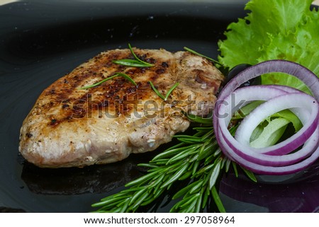 Grilled pork steak with rosemary on the wood background