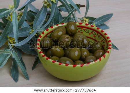 Green marinated olives in the bowl leaves