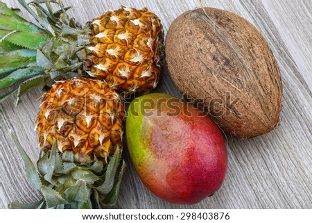 Pineapple, mango and coconut on the wood background