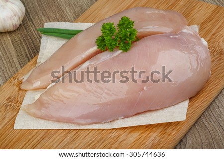 Raw chicken breast with parsley leaves on the wood background