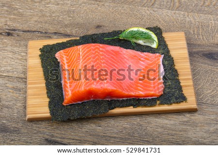 Salmon fillet on nori background with dill and lemon