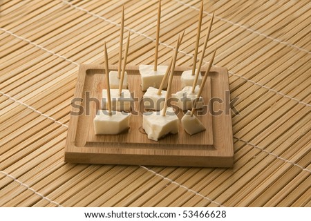 served white cheese on a wooden board with tooth pics