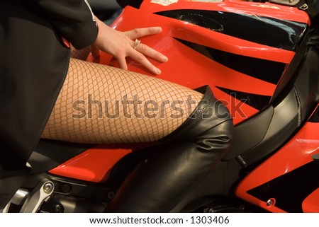 Woman sits on motorbike. Woman leans her hand. Fishnet. Nice legs.