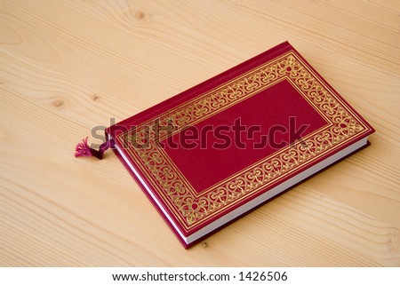 Book. Book on table. Red book. Book with red cover and arabesque decoration. Wood background.