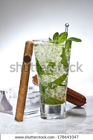 mojito cocktail and ashtray with cigar on wet table in gradient background