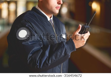 a cut face close up in a security guard with a portable wireless transceiver on a blurry background