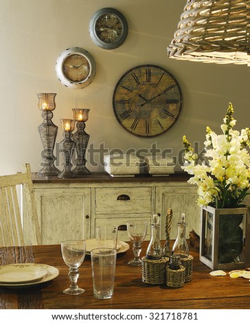 a close up in a table with dinnerware set and with a buffet on background with candles and clocks on the wall