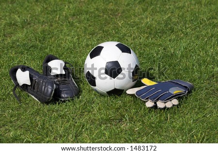 Soccer boots, ball and gloves laid out on grass