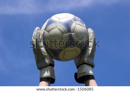 Goalie holding soccer ball with sky background