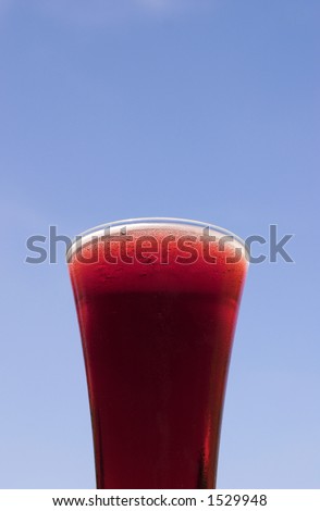 Glass of fruit beer against a sky background