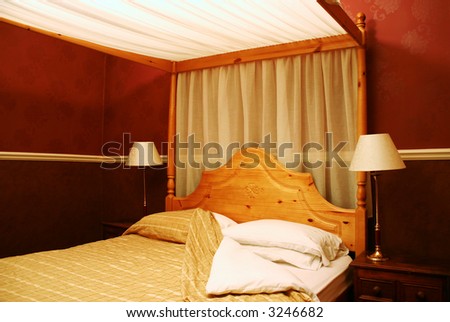 old-fashioned four poster hotel bed with open duvet