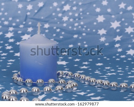 A blue candle with a silver string decorated for Christmas