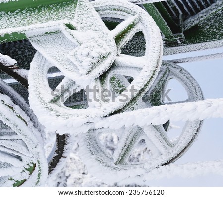 Frozen metal wheel or pulley covered in ice and snow on an exterior structure in harsh winter climatic conditions