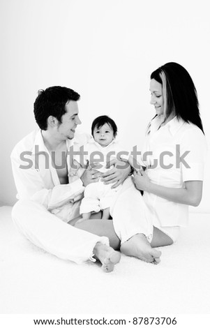 A young happy family with their 4  month old son sitting in bed