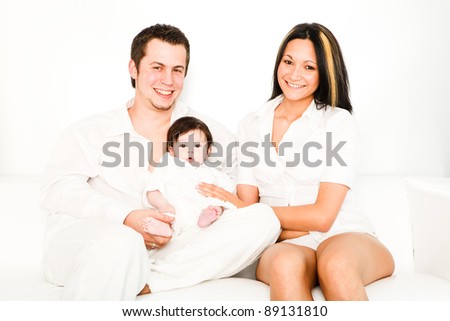 A young happy family with their 4  month old son sitting in bed