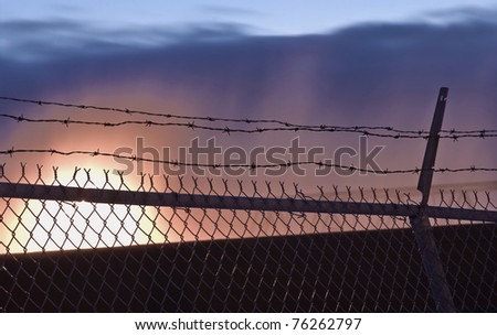 Barbed-wire fence in front of spectacular sunset.