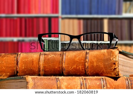 Old books and eye glasses with sharp vision through them on the books against the indistinct (unsharp, not in focus) background - Concept of visual acuity return