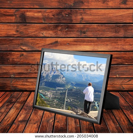 Picture frame with photo of Rocky Mountains  Bow river landscape and man looking down from Sulfur mountain at (Banff National Park. Alberta.Canada) on the wooden panel background.Collage of my photos