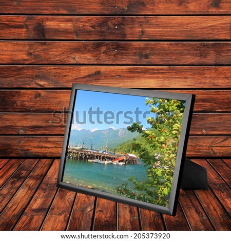 Picture frame with photo of Vancouver Island wooden mooring (Vancouver Island, British Columbia, Canada) on the wooden panel background. Collage of my photos