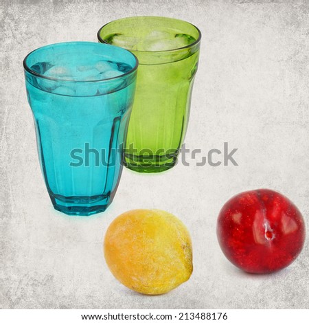 Textured old paper background with Color ripe plums and drink glasses with ice cooled drink (water) still life. Vintage style image