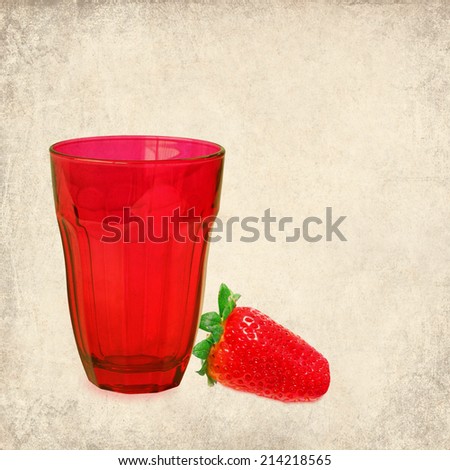 Textured old paper background with red drink glass and only ripe strawberry. Still life. Vintage style image