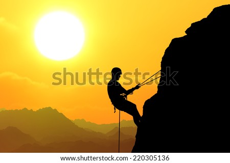 Silhouette of man climbing on rock (mountain) at sunset