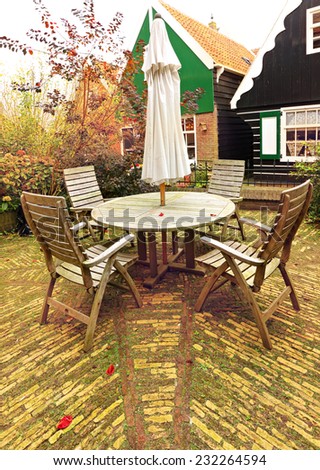 Wooden table and chairs on the yard\'s stone tile floor of autumn open space