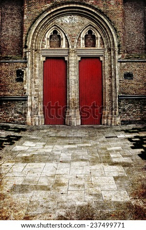 Red doors of gothic style brick building and tile road ( Europe,Belgium). Ancient architecture theme. Textured old paper background.Photo in retro style. Aged textured photo in retro style
