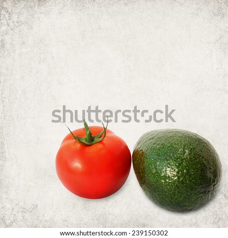Tomato and avocado fruits on textured old paper background. Photo in retro style. Paper texture.