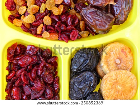 Dried fruits in plastic container for food storage. Raisin, cranberry, fig, plum and date fruits background