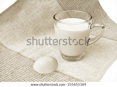 Glass mug of milk and egg on linen cloth background. Vintage effect style pictures