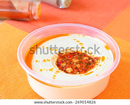 Hummus salad pate with grains of peas and hot spices in the plastic container