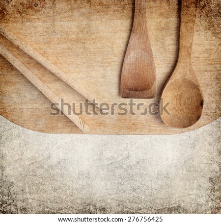 Different wood kitchen tools on the  old wood kitchen cutting board with textured paper  copy space background