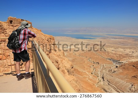 Panoramic view of Judaean Desert and Dead See from Masada ancient fortification  and man watching down from cliff. Masada fortification of the 1st century, popular sight ,UNESCO World Heritage,Israel