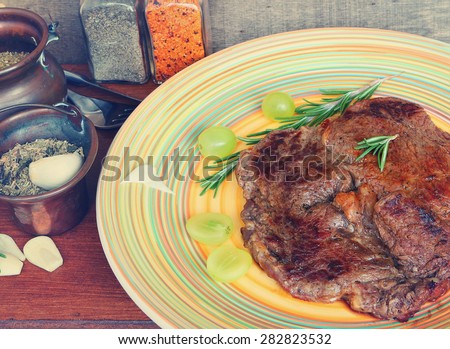 Meat (low fat beef steak) with herbs and grapes of Mediterranean cuisine. Image done in vintage retro instagram style