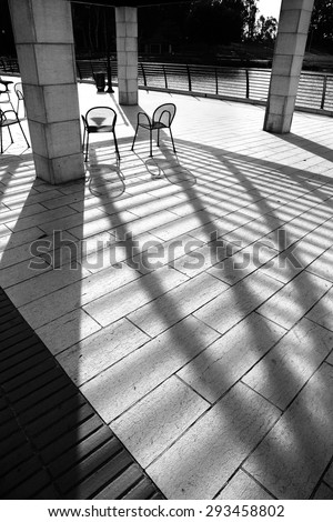 Outdoor chairs with strong shadows natural effect. Counter light. Objects, light and shadows. Black and white.