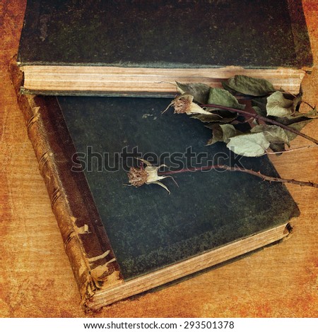 Vintage books and dry rose flower on a wood background. Photo in retro style on textured old paper background