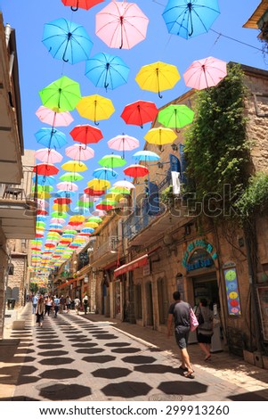 JERUSALEM,ISRAEL - JULY 19,2015:Colorful umbrellas floating magically in the sunny blue sky above pedestrian Yoel Moshe Salomon Street with galleries, ceramics, arts jewelry and clothing shops