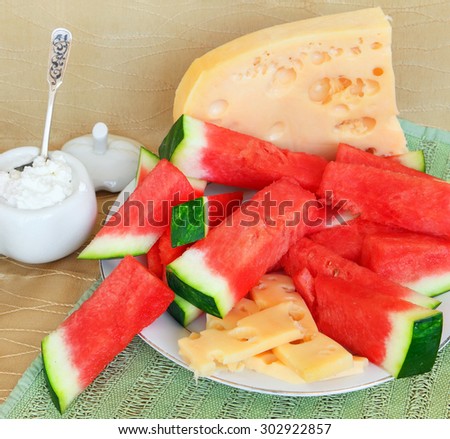 Ripe watermelon, cheese and cottage cheese, served in simple country style with flowers. Healthy food for lunch or snack. Selective focus